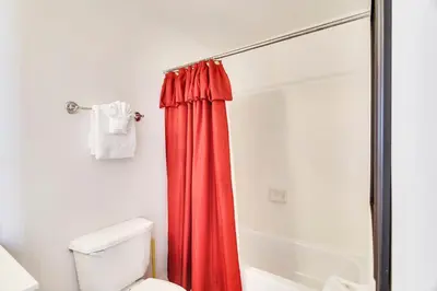 a bathroom with a red shower curtain next to a toilet at Ocean Villa Condos #1801 by Book That Condo in Panama City Beach
