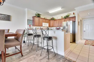 a kitchen with a bar with stools and a refrigerator at Ocean Villa Condos #1801 by Book That Condo in Panama City Beach