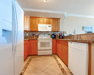 a kitchen with wooden cabinets and white appliances at Twin Palms Resort #601 by Book That Condo in Panama City Beach