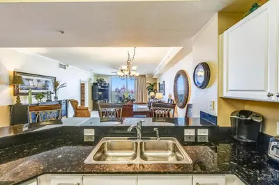 a kitchen with a sink and a living room at Tidewater Beach Resort #508 by Book That Condo in Panama City Beach