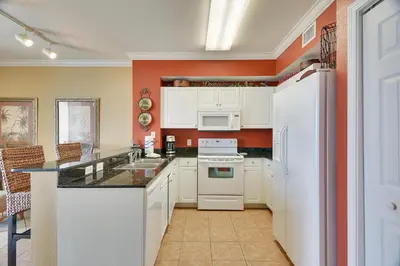 a kitchen with white appliances and an orange wall at Tidewater Beach Resort #2014 by Book That Condo in Panama City Beach