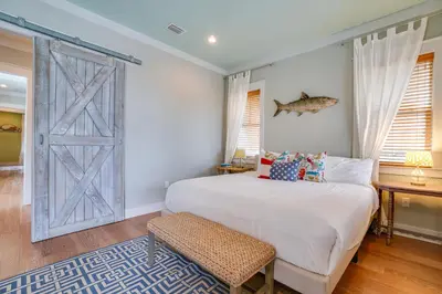 a bedroom with a bed and a door with a fish on the wall at 30A Blue Crab Cottage by Panhandle Getaways in Rosemary Beach