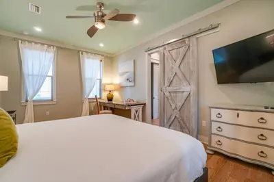 a bedroom with a white bed and a flat screen tv at 30A Blue Crab Cottage by Panhandle Getaways in Rosemary Beach