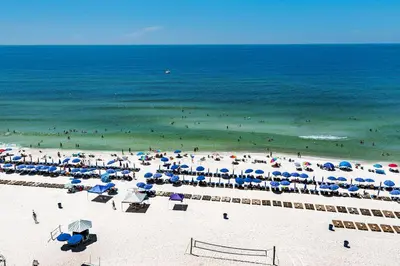 a beach with many umbrellas and people in the ocean at Calypso 1-1809 East in Panama City Beach