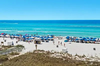 a group of people on a beach with umbrellas and the ocean at Ocean Villa 405 in Panama City Beach