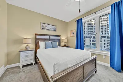 a bedroom with a bed and a window with blue curtains at Grand Panama 1-409 in Panama City Beach