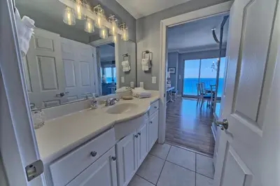 a white bathroom with a sink and a mirror at Cozy Oceanfront Condo with Beachside Pool - Unit 1602 in Panama City Beach