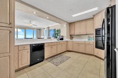a kitchen with wooden cabinets and black appliances at Hidden Dunes 1401 in Panama City Beach
