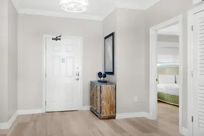 a white bedroom with a door and a bed at Hidden Dunes 304 in Panama City Beach