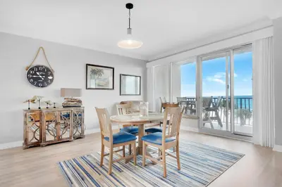a dining room with a table and chairs and a clock at Hidden Dunes 304 in Panama City Beach