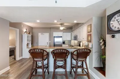a kitchen with three bar stools and a counter at Astonishing Beacfront Condo with 360 sqft Balcony Facing the Ocean - Unit 0302 in Panama City Beach