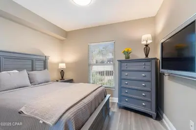 a bedroom with a bed and a dresser with a flat screen tv at Astonishing Beacfront Condo with 360 sqft Balcony Facing the Ocean - Unit 0302 in Panama City Beach