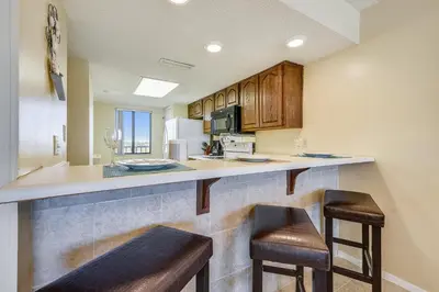 a kitchen with two bar stools and a counter top at Commodore Resort #707 by Book That Condo in Panama City Beach