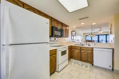 a kitchen with wooden cabinets and a white refrigerator at Commodore Resort #707 by Book That Condo in Panama City Beach