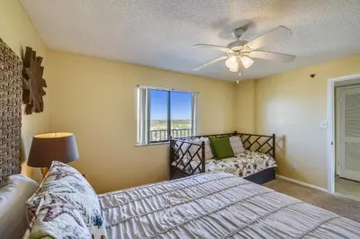 a bedroom with a bed and a ceiling fan at Commodore Resort #707 by Book That Condo in Panama City Beach