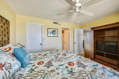 a bedroom with a bed and a ceiling fan at Commodore Resort #707 by Book That Condo in Panama City Beach