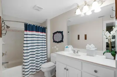 a bathroom with a sink and a toilet and a mirror at Hidden Dunes 402 in Panama City Beach
