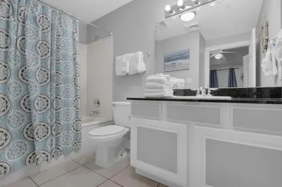 a bathroom with a toilet and a sink and a mirror at Calypso 1-203 East in Panama City Beach
