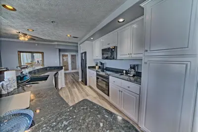 a kitchen with white cabinets and granite counter tops at Spacious Tropical Condominium at 17th Floor with Beach and Pool Access - Unit 1707 in Panama City Beach