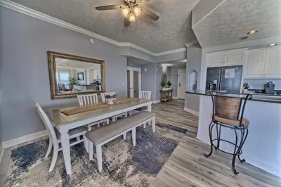 a dining room and kitchen with a table and chairs at Spacious Tropical Condominium at 17th Floor with Beach and Pool Access - Unit 1707 in Panama City Beach