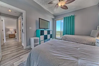 a bedroom with two beds and a flat screen tv at Spacious Tropical Condominium at 17th Floor with Beach and Pool Access - Unit 1707 in Panama City Beach