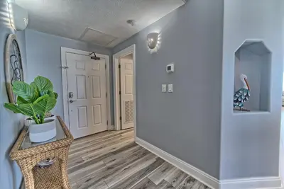a hallway with blue walls and a plant in a chair at Spacious Tropical Condominium at 17th Floor with Beach and Pool Access - Unit 1707 in Panama City Beach