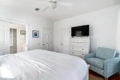 a bedroom with a bed and a chair and a television at Pure Joy* in Santa Rosa Beach