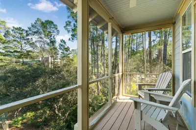 two chairs on a porch with a view of trees at Pure Joy* in Santa Rosa Beach