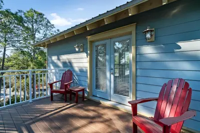 two red chairs sitting on the front porch of a house at Pure Joy* in Santa Rosa Beach