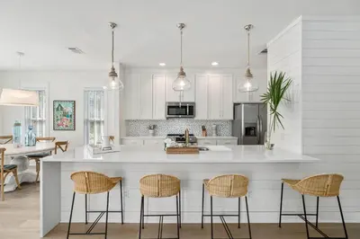 a kitchen with white cabinets and a island with bar stools at 248 Beach Bike Way in Inlet Beach