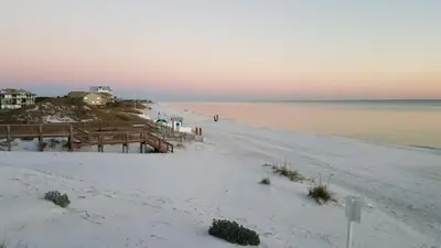 a sandy beach with a pier and the ocean at Chivas Apartment on 30A in Santa Rosa Beach