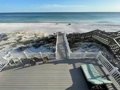 a boardwalk leading to a beach with chairs and the ocean at Chivas Apartment on 30A in Santa Rosa Beach
