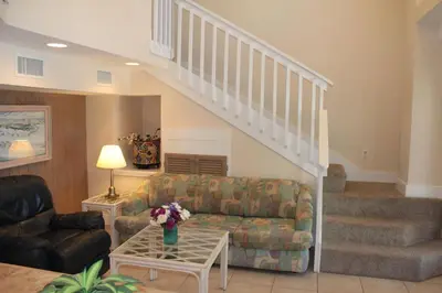 a living room with a couch and a staircase at Chivas Apartment on 30A in Santa Rosa Beach