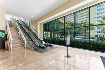 a lobby of a building with escalators and windows at Flipflop Paradise Unit 625 in Panama City Beach