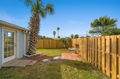 a backyard with a palm tree and a fence at Endless Summer's 514 in Panama City Beach
