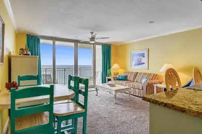 a kitchen and living room with a table and a couch at Emerald Beach #1426 by Book That Condo in Panama City Beach