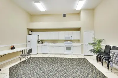 a kitchen with white cabinets and a table and chairs at Celadon Beach Resort #1104 by Book That Condo in Panama City Beach