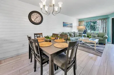 a dining room with a table and chairs and a clock at Edgewater Golf Villa 1409 in Panama City Beach