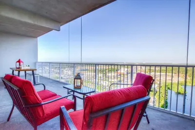a balcony with two red chairs and a table at Large 3 Bd Penthouse 2034 In Laketown, Great Views and Amenities! in Panama City Beach