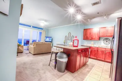 a kitchen with red cabinets and a living room at Large 3 Bd Penthouse 2034 In Laketown, Great Views and Amenities! in Panama City Beach