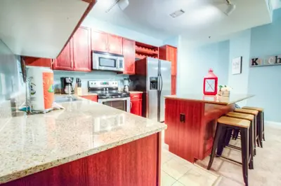 a kitchen with red cabinets and stainless steel appliances at Large 3 Bd Penthouse 2034 In Laketown, Great Views and Amenities! in Panama City Beach