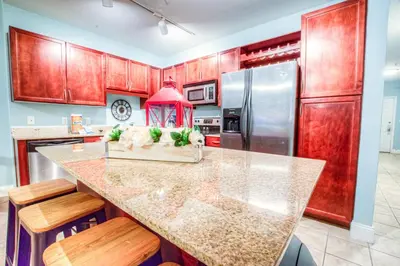a kitchen with wooden cabinets and a kitchen island with chairs at Large 3 Bd Penthouse 2034 In Laketown, Great Views and Amenities! in Panama City Beach