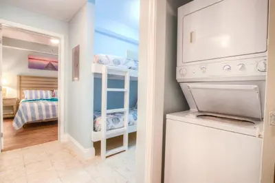 a laundry room with a washer and dryer and a bedroom at Laketown Wharf 1238 - Brand New End Unit With Wrap Around Balcony in Panama City Beach