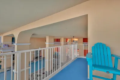 a balcony with a blue chair and a swimming pool at Calypso 3-205 in Panama City Beach