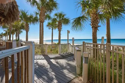 a wooden walkway to the beach with palm trees at Calypso 3-205 in Panama City Beach