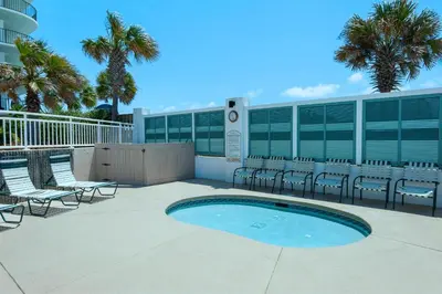 a patio with chairs and a pool in front of a building at Watercrest 402 in Panama City Beach