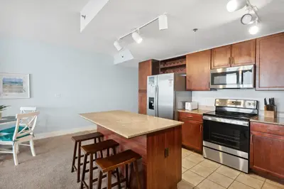 a kitchen with wooden cabinets and a counter top at Spacious Resort Condo with Breathtaking Gulf Views! by Dolce Vita Getaways PCB in Panama City Beach
