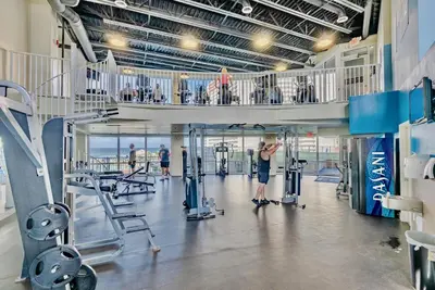 a gym with a man exercising in the gym at Spacious Resort Condo with Breathtaking Gulf Views! by Dolce Vita Getaways PCB in Panama City Beach