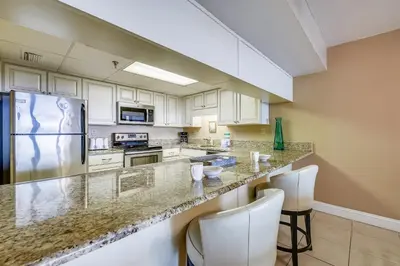 a kitchen with white cabinets and a granite counter top at Watercrest #1206 by Book That Condo in Panama City Beach