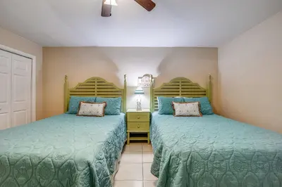 two beds in a room with green comforter at Watercrest #1206 by Book That Condo in Panama City Beach